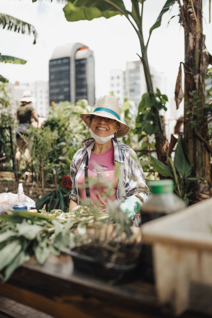 Happy woman gardening on a rooftop garden in the city, enjoying nature and urban farming.