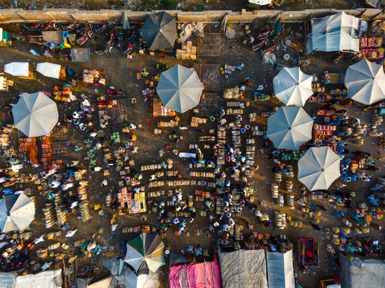 Aerial view of a bustling market in Punjab, showcasing colorful umbrellas and various stalls.