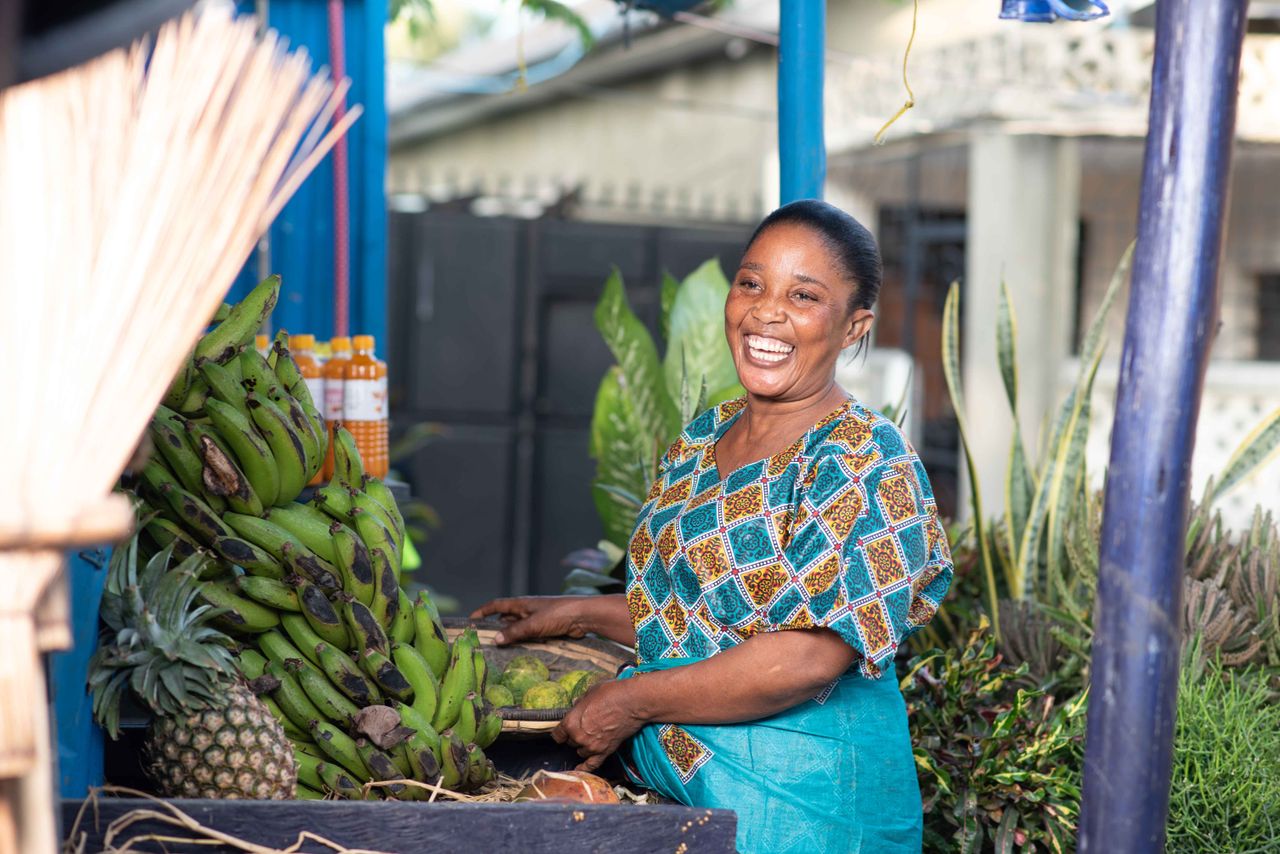 A joyful vendor selling fresh bananas and pineapples at a local market in Dar es Salaam, Tanzania.